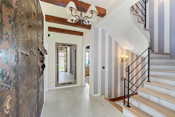A staircase with a black metal railing and beige steps, leading to a landing with a white wall and a light fixture.