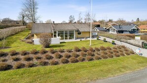 A modern house with a large glass window, a flagpole, and a well-maintained lawn. - 2 bedroom nice home in Juelsminde (Juelsminde)