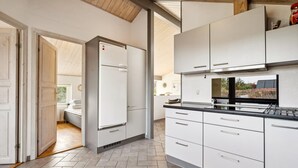 A modern kitchen with white cabinets, a built-in oven, and a window overlooking a garden. - 2 bedroom nice home in Juelsminde (Juelsminde)