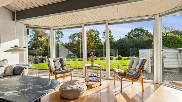 A spacious room with large glass doors leading to a garden, furnished with a sofa, two armchairs, and a round table. - 2 bedroom nice home in Juelsminde (Juelsminde)