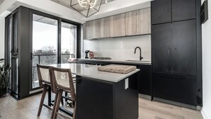 Una cocina moderna con una isla central, armarios negros y un ventanal con vistas a la ciudad.