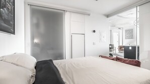 Una habitación de hotel moderna con una cama grande, un armario y un espejo.