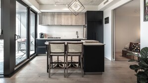 Una cocina moderna con una isla central, armarios negros y un ventanal grande.