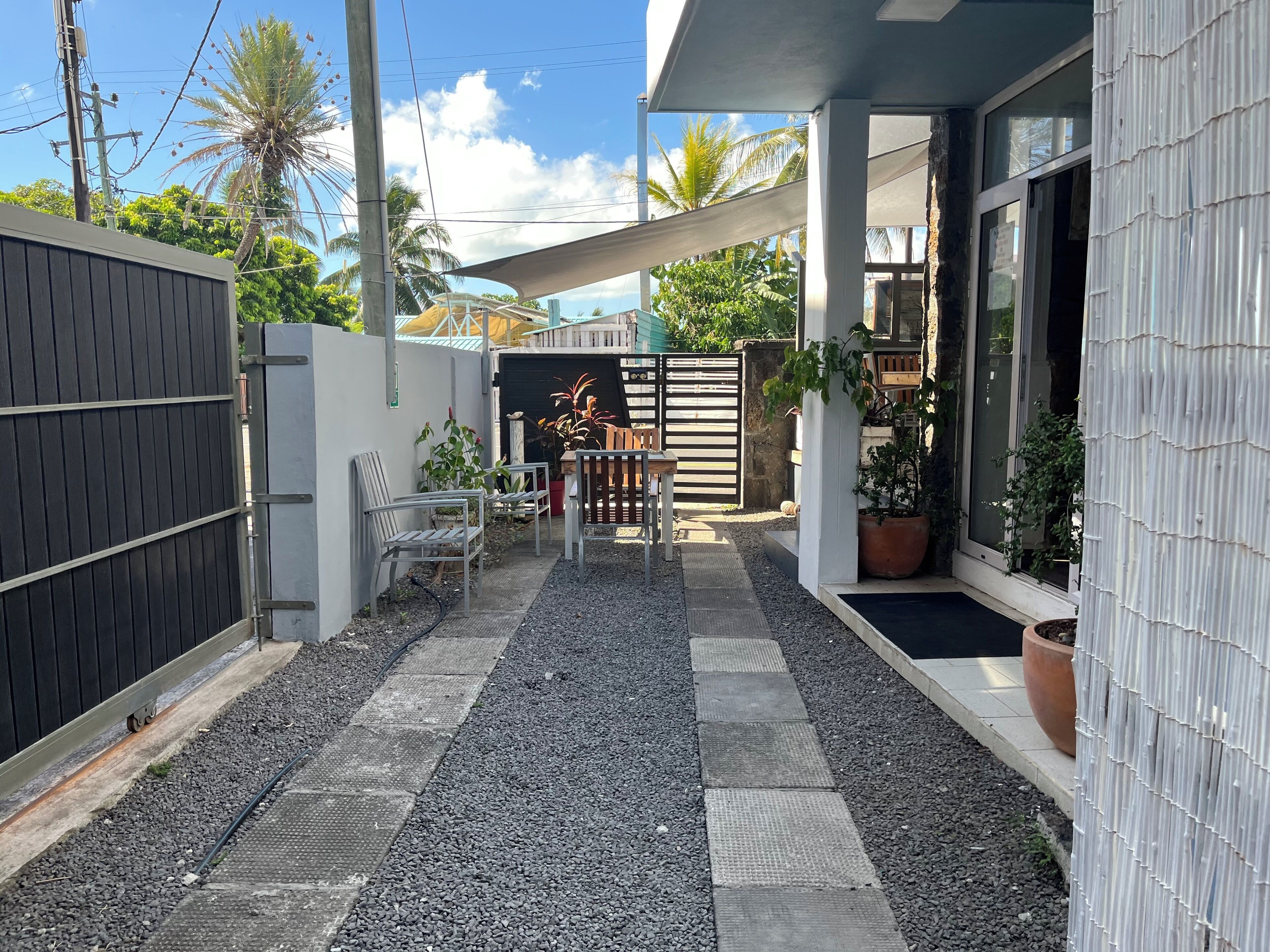 Eine moderne Terrassenanlage mit Kiesweg, Metallstühlen und einem Holztisch.