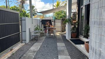 Eine moderne Terrassenanlage mit Kiesweg, Metallstühlen und einem Holztisch.