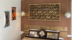 Een slaapkamer met een houten hoofdeinde, een decoratief wandtapijt en twee wandlampen.