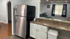 Eine Küche mit Edelstahlkühlschrank, weißen Schränken, einer Granit-Arbeitsplatte und einem Mülleimer.