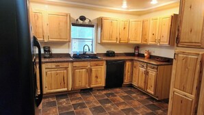 Una cocina con armarios de madera, un lavavajillas negro y piso de baldosas.