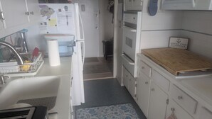 Eine kleine Küche mit Spüle, Geschirrgestell, Schneidebrett und Kühlschrank.