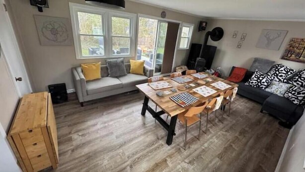 A cozy living room with a wooden dining table, a grey sofa, and a black and white patterned sofa.