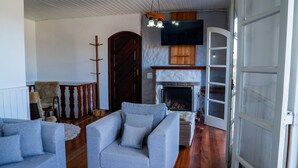 A living room with a fireplace, a television mounted above it, and a door leading to another room.