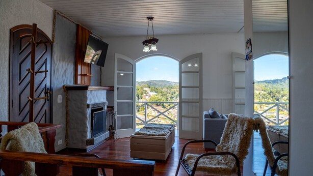 A cozy room with a fireplace, a television, and a view of a mountainous landscape through open doors.