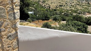 Ein Balkon mit Blick auf eine gebirgige Landschaft, Steinmauern und ein Strohdach.