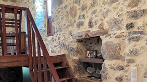 Eine Holztreppe vor einer Steinsäule, ein kleines Regal mit Dekoration und ein Fenster, das natürliches Licht hereinlässt.