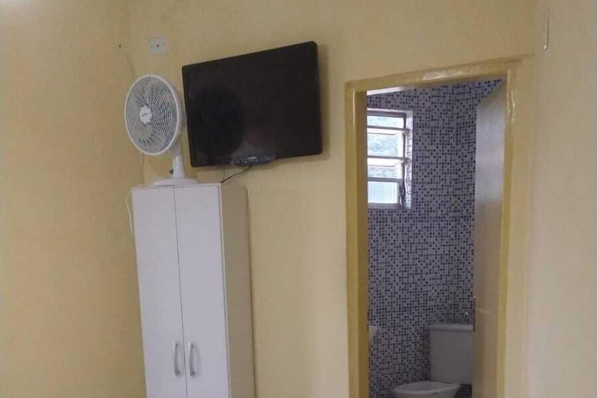 Une chambre avec deux lits, une armoire, un téléviseur et une salle de bain visible à travers une porte ouverte.