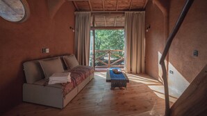 Une pièce chaleureuse avec un plancher en bois, un canapé, une petite table et une fenêtre avec des rideaux.