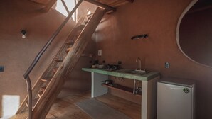 Une cuisine compacte avec un escalier en bois, un petit réfrigérateur et les équipements de base.