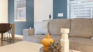A living room with a grey sofa, a patterned throw pillow, a yellow vase, and a white vase on a coffee table. - Landing South San Antonio (San Antonio)