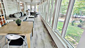 Eine überdachte Terrasse mit Esstisch, Stühlen und einer Couch.