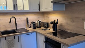 A modern kitchen with white cabinetry, a black faucet, a built-in oven, and a wooden countertop. - Apartment on garden level, between Monaco and Italy, in quiet country setting (Roquebrune-Cap-Martin)
