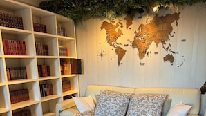 A neatly arranged bedroom with a large bed, a bookshelf filled with books, and a world map on the wall. - Apartment on garden level, between Monaco and Italy, in quiet country setting (Roquebrune-Cap-Martin)