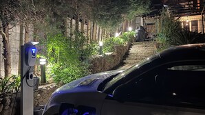 A car charging at a station with a stone wall and greenery in the background. - Apartment on garden level, between Monaco and Italy, in quiet country setting (Roquebrune-Cap-Martin)