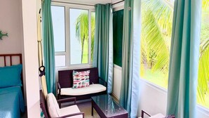 A room with a bed, a sofa, a small table, and a ceiling fan.