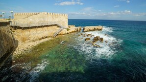 A coastal fortification with a staircase leading to a viewing platform, overlooking the sea. - RE CARLO - Ortigia Luxury Suite (Siracusa)