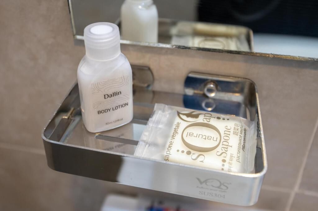 A bathroom shelf with a bottle of Dallin body lotion and a packet of Jeunet soap.