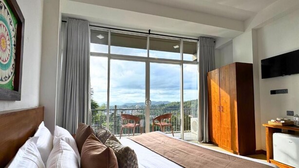 Habitación de hotel con una cama grande, un armario de madera, televisión y balcón con vistas a la ciudad.