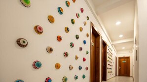 Un pasillo con una pared decorada con objetos circulares y coloridos que recuerdan a flores.
