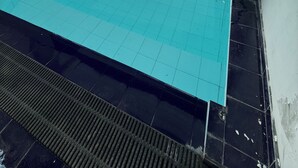 Una piscina interior con agua cristalina y azul, rodeada por una solana con baldosas y una barandilla metálica.