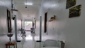 A corridor with a round table and chairs, a potted plant, and a window with a view.