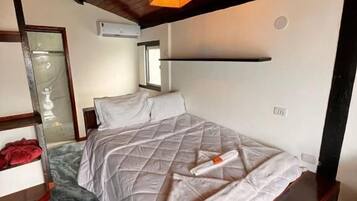 A bedroom with a bed, a wooden headboard, a marble floor, and a hanging light fixture.