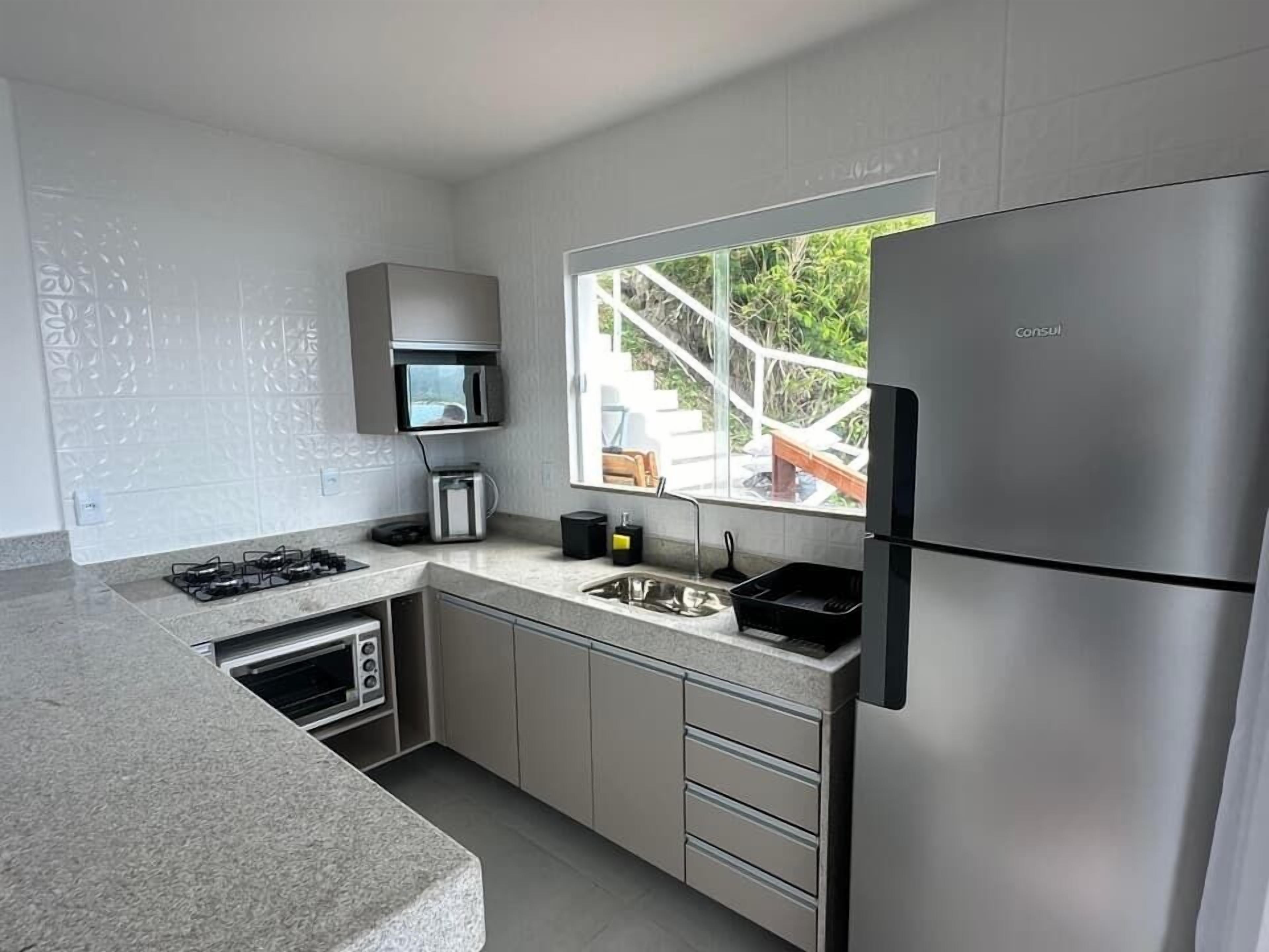 A modern kitchen with a built-in microwave, a gas stove, a sink, and a stainless steel refrigerator.