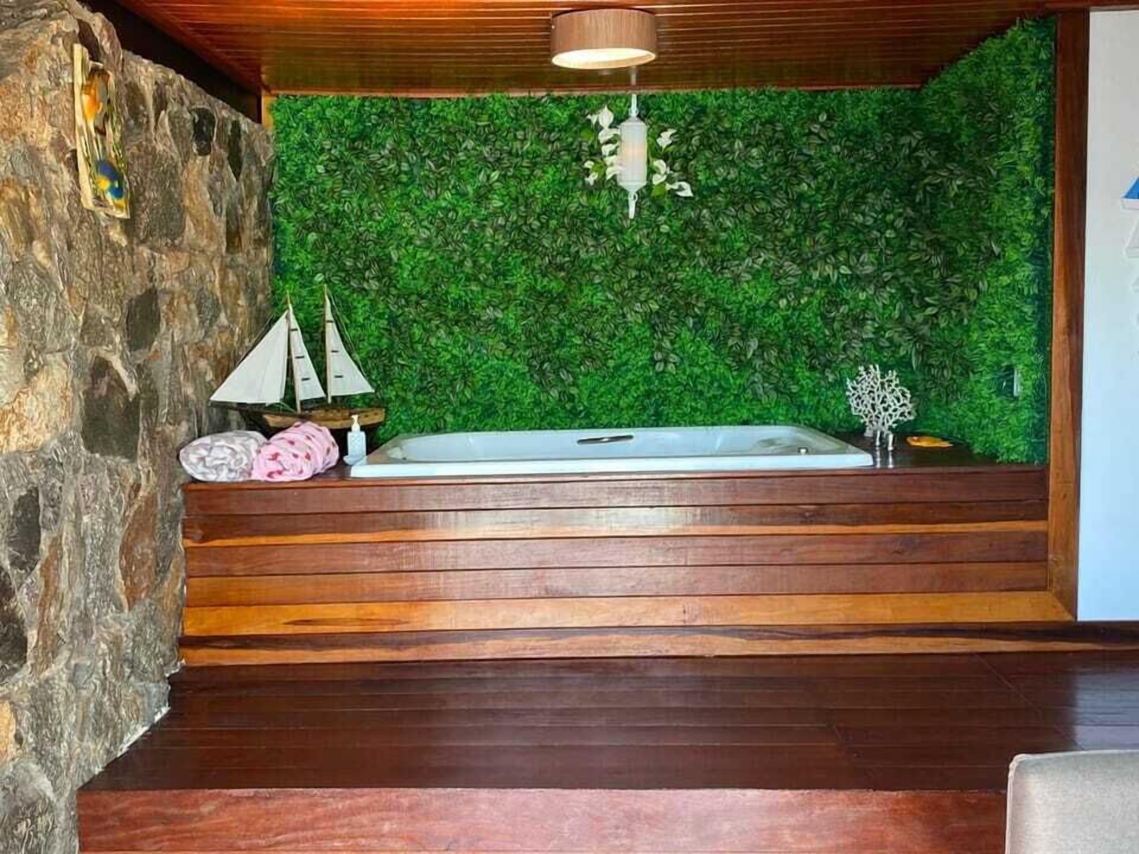 Un espace de détente avec un banc en bois, une baignoire et un mur végétal.