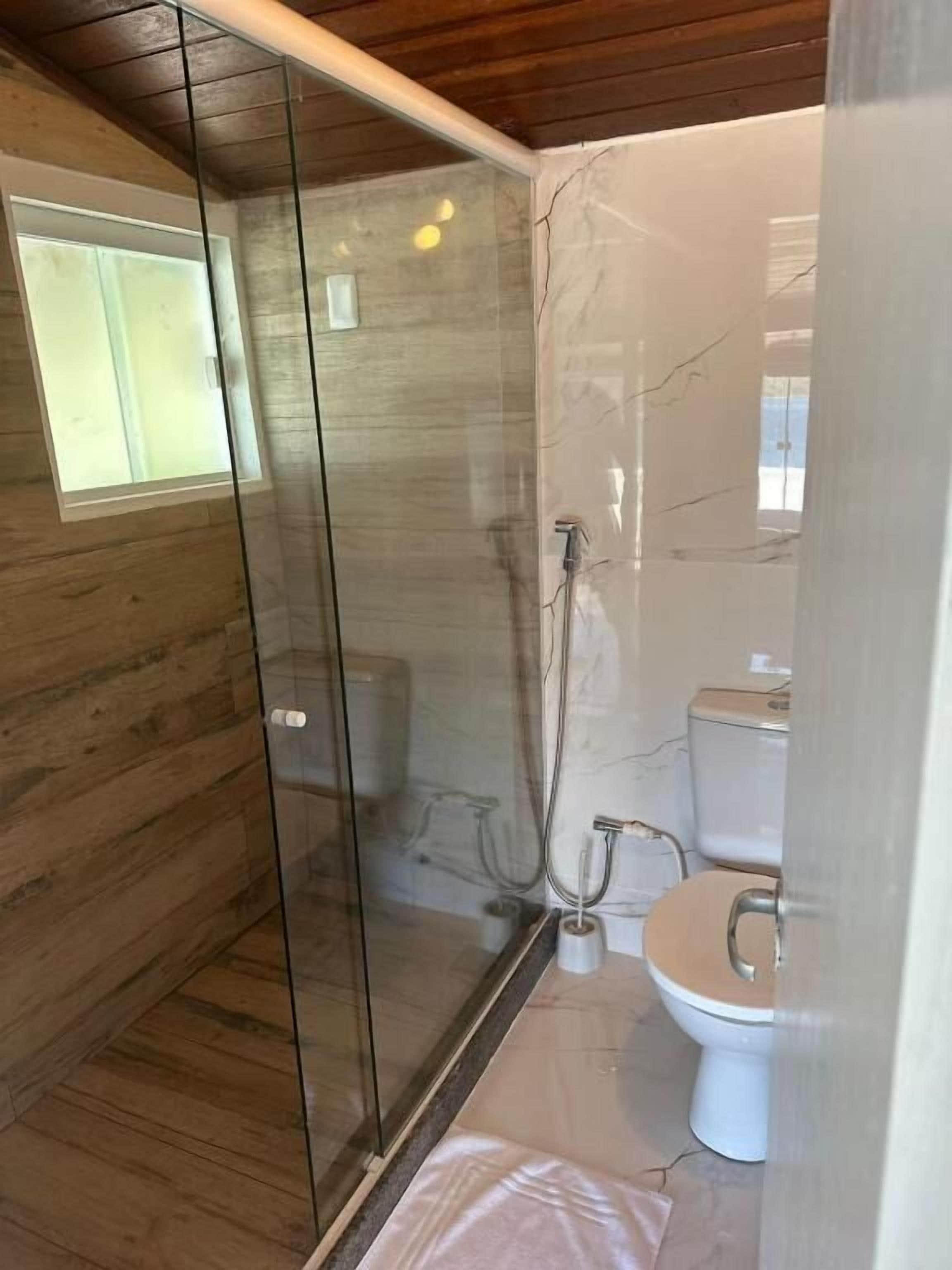 Un bagno moderno con box doccia in vetro, pavimento in legno e parete in marmo.