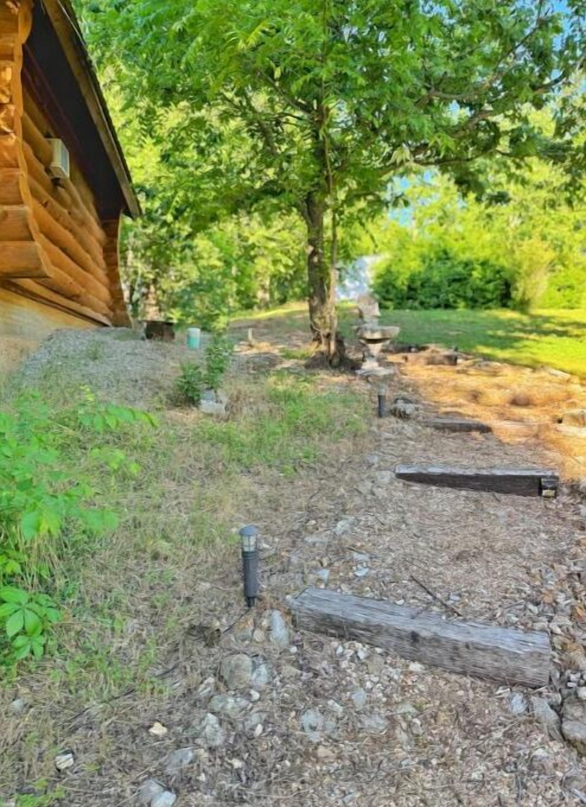 A wooden cabin with a gravel path leading to a wooden bench.