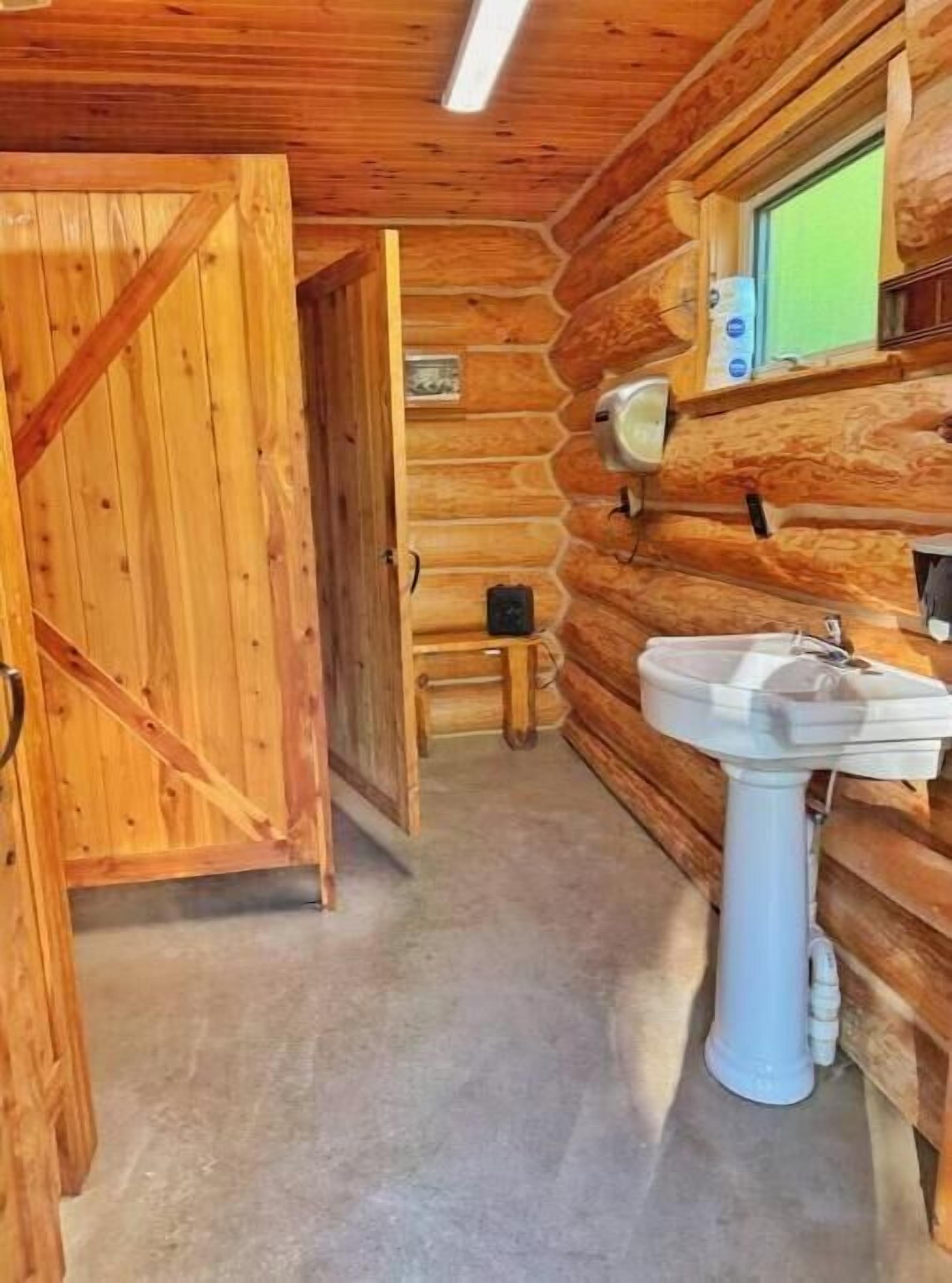 L’intérieur d’une cabane en bois, avec une porte en bois, un évier et une fenêtre.