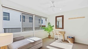 A modern living room with a sofa, a dining table, and a potted plant. - Thirty-Nine Albatross (Apartment 8) (Gold Coast)