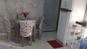 Una cocina pequeña con un refrigerador blanco, una mesa de comedor con sillas y una alfombra roja en el suelo.