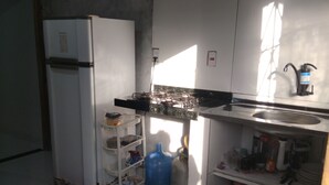 Cocina pequeña con refrigerador, estufa a gas y estanterías básicas.