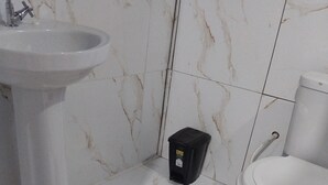 Un baño con un lavamanos blanco, un inodoro y una alfombra roja en el suelo.