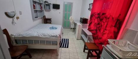 Ein Schlafzimmer mit einem Bett, einem Schreibtisch, einem Stuhl, einem Fernseher und einem Kleiderschrank.