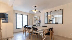 A dining area with a table set for six, a bookshelf, and a large mirror on the wall. - Proche mer très agréable appt de 2 ch pour 5 pers (Le Touquet-Paris-Plage)