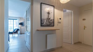 A hallway with a framed photograph of a Paris landmark, a white radiator, and a door. - Proche mer très agréable appt de 2 ch pour 5 pers (Le Touquet-Paris-Plage)