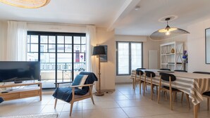 A modern living room with a large TV, a dining table, and a sofa. - Proche mer très agréable appt de 2 ch pour 5 pers (Le Touquet-Paris-Plage)