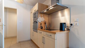 A compact kitchen with a microwave, oven, and coffee maker on the countertop. - Proche mer très agréable appt de 2 ch pour 5 pers (Le Touquet-Paris-Plage)
