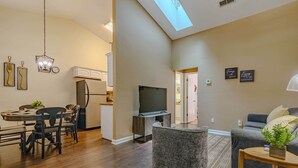A modern living room with a dining area, a kitchen, and a TV. - Ultimate Getaway: Yard, BBQ & Games (Gainesville)
