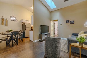A modern living room with a dining area, a kitchen, and a TV.